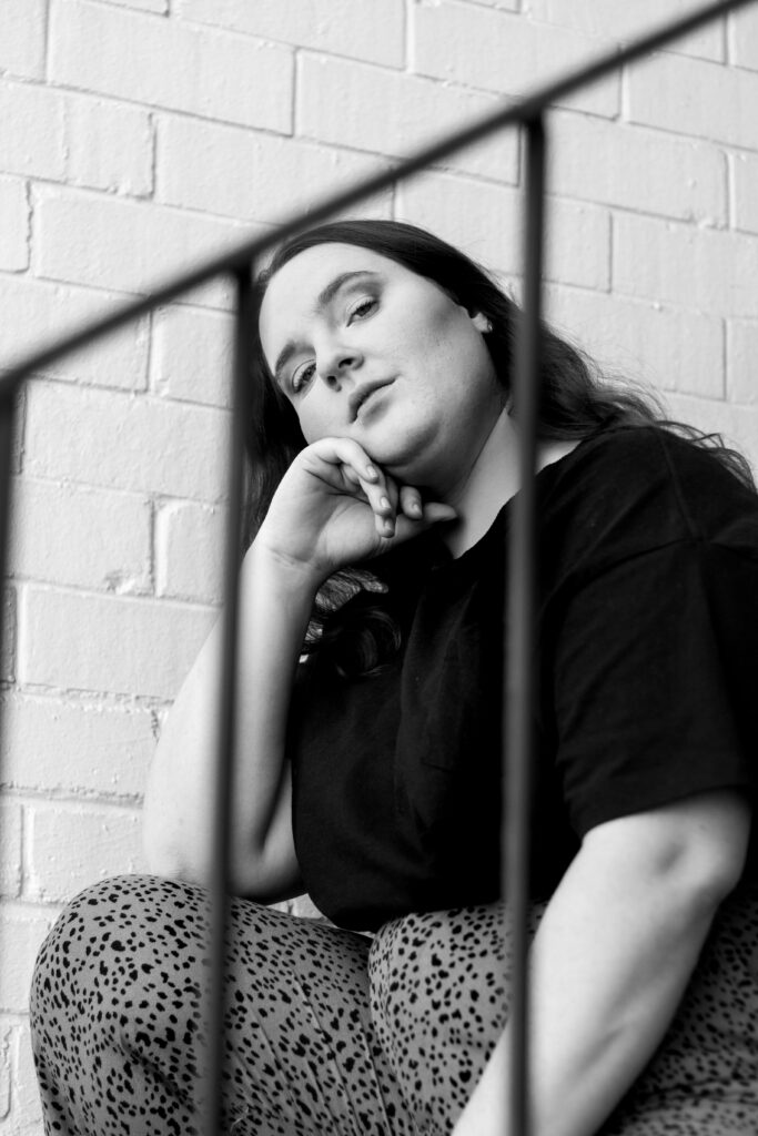 Black and white photo of Sarah sitting on stairs.